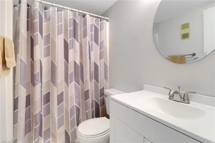 Bathroom featuring vanity, toilet, and curtained shower