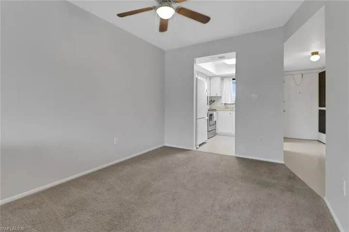 Empty room with ceiling fan and light colored carpet