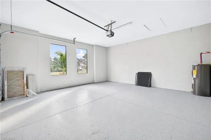 Spacious garage with light gray speckled epoxy flooring, two vertical windows, and a water heater