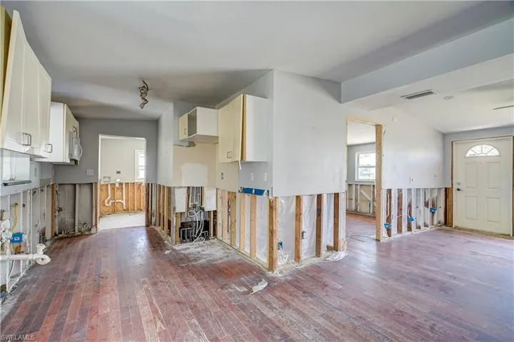 Kitchen with hardwood / wood-style floors, white cabinetry, and lofted ceiling