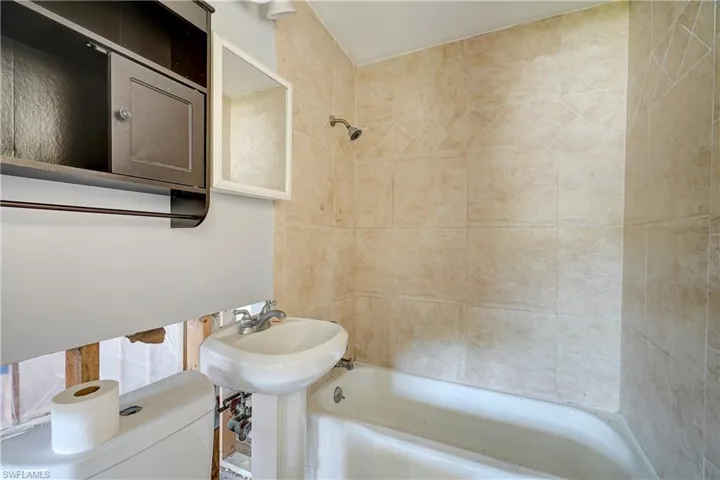 Bathroom with tiled shower / bath and toilet