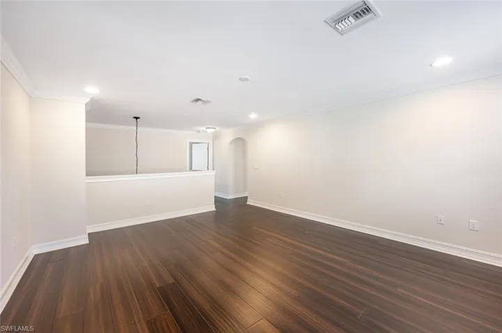 Unfurnished room with crown molding and dark wood-type flooring