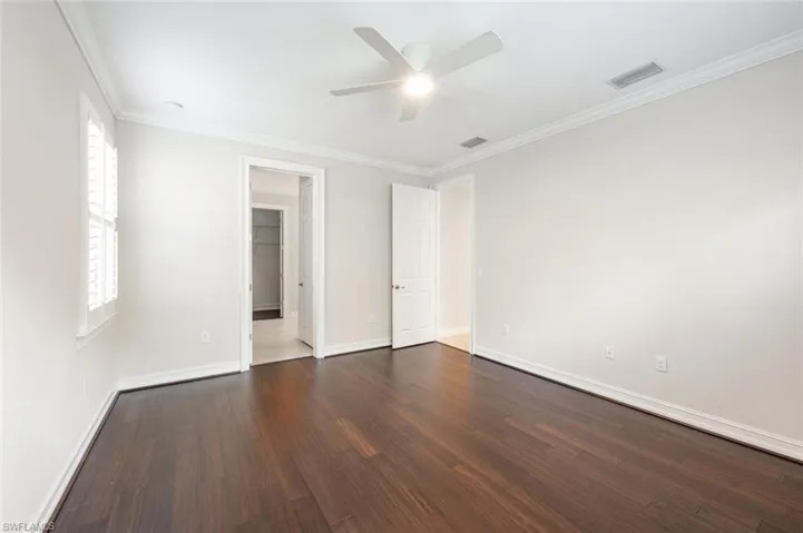 Spare room with a healthy amount of sunlight, crown molding, and dark wood-type flooring