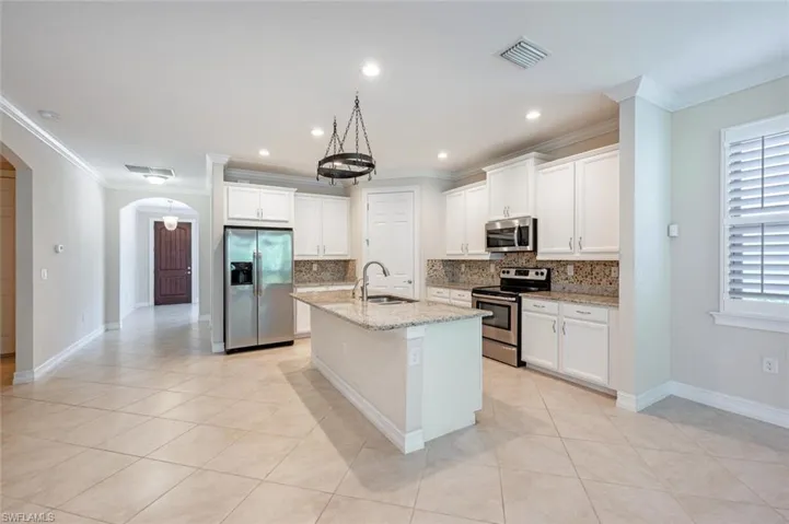 Kitchen featuring stainless steel appliances, tasteful backsplash, a center island with sink, and sink