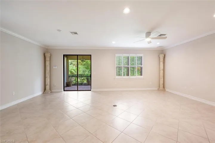 Tiled empty room with ceiling fan, ornamental molding, and decorative columns