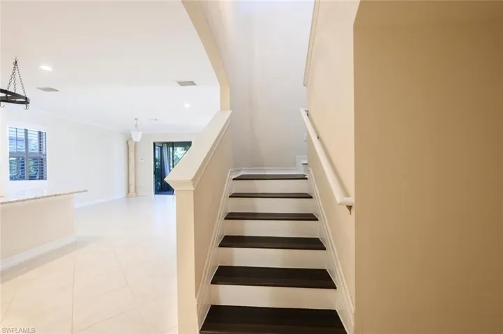 Staircase with crown molding and a healthy amount of sunlight