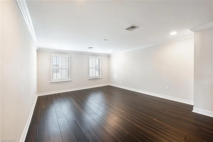 Empty room featuring dark wood-type flooring and ornamental molding