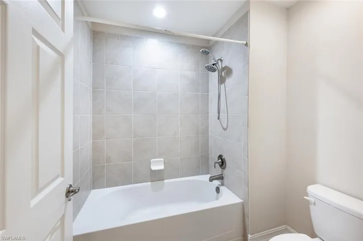 Bathroom featuring tiled shower / bath combo and toilet