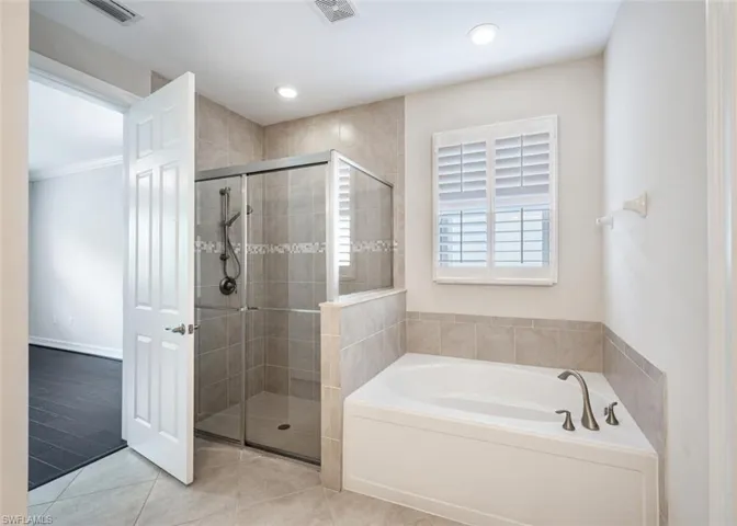 Bathroom featuring tile patterned flooring and shower with separate bathtub