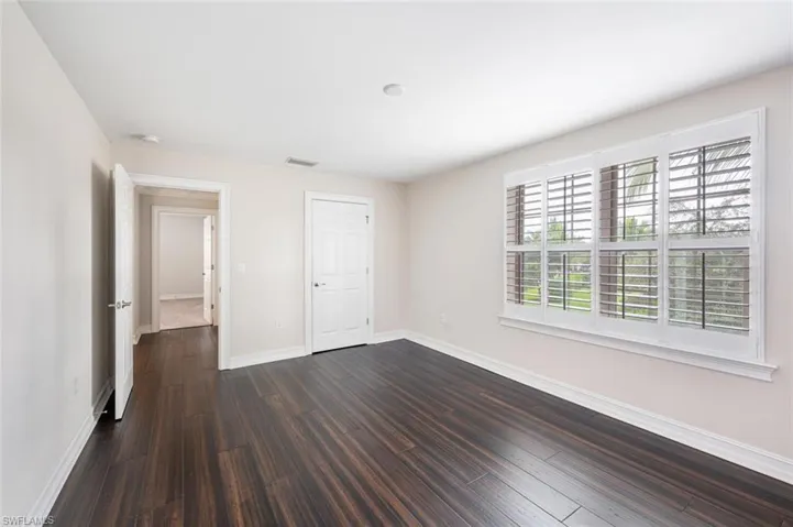 Unfurnished bedroom with dark hardwood / wood-style flooring and a closet
