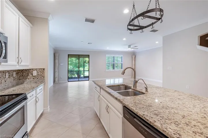 Kitchen featuring ceiling fan, sink, stainless steel appliances, decorative backsplash, and white cabinets