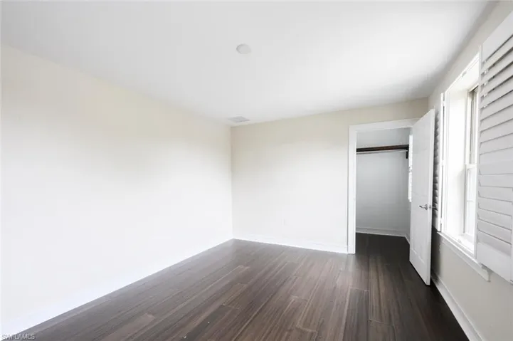 Unfurnished bedroom featuring a closet and dark hardwood / wood-style floors