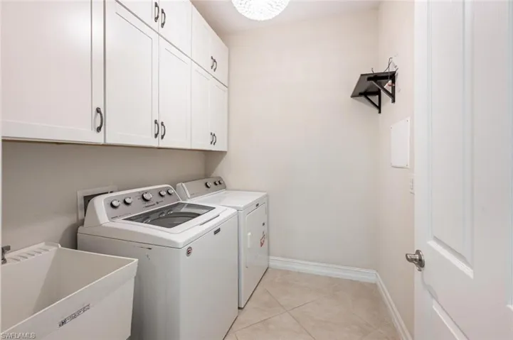 Washroom with separate washer and dryer, sink, light tile patterned floors, and cabinets