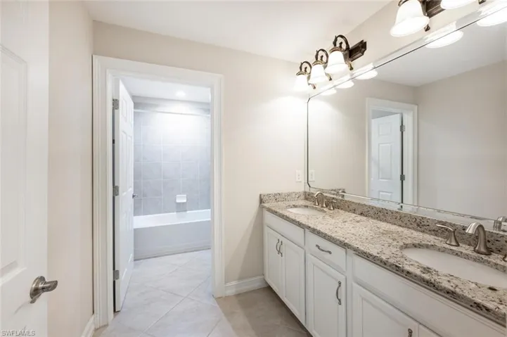 Bathroom featuring tile patterned flooring, vanity, and tiled shower / bath combo