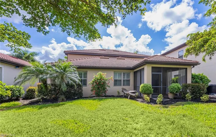 Rear view of house featuring a sunroom and a lawn