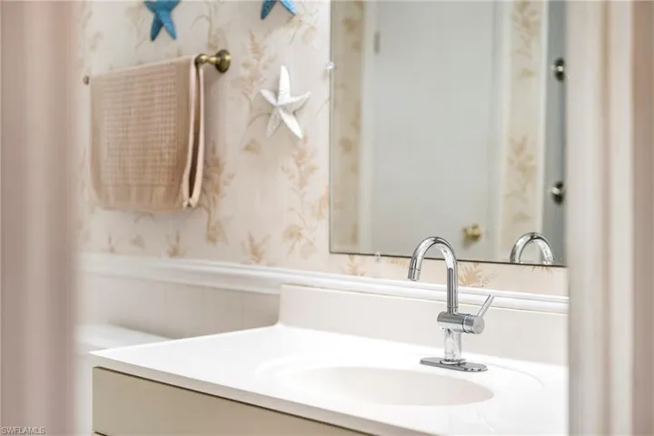 Bathroom with a wainscoted wall, vanity, wallpapered walls, and a decorative wall