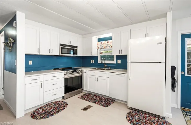 Kitchen with stainless steel appliances, white cabinetry, and light countertops