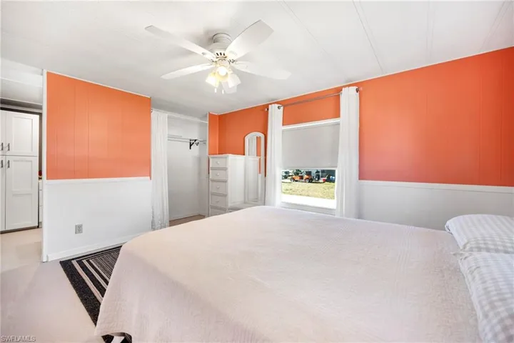 Bedroom with ceiling fan, wooden walls, and wainscoting