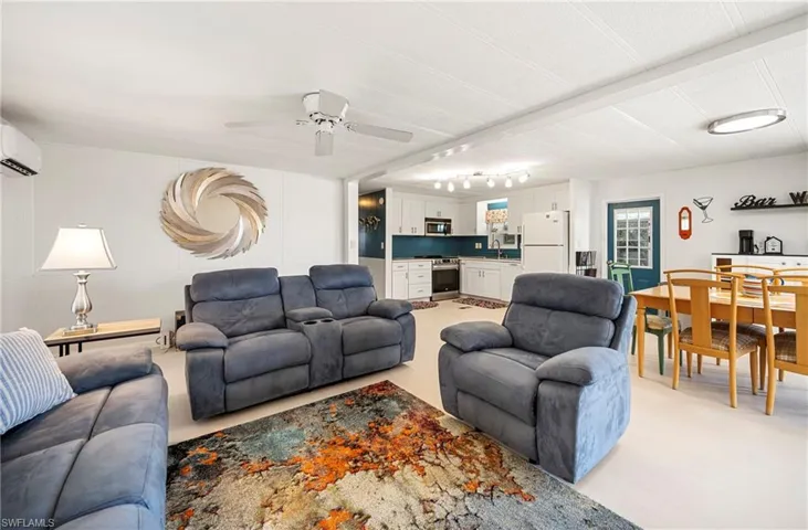 Living area with ceiling fan and an AC wall unit