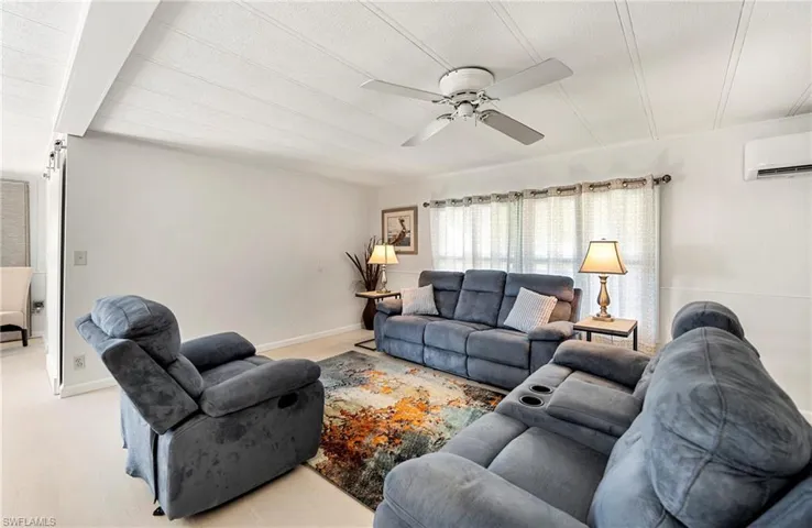 Living room with a ceiling fan and a wall unit AC