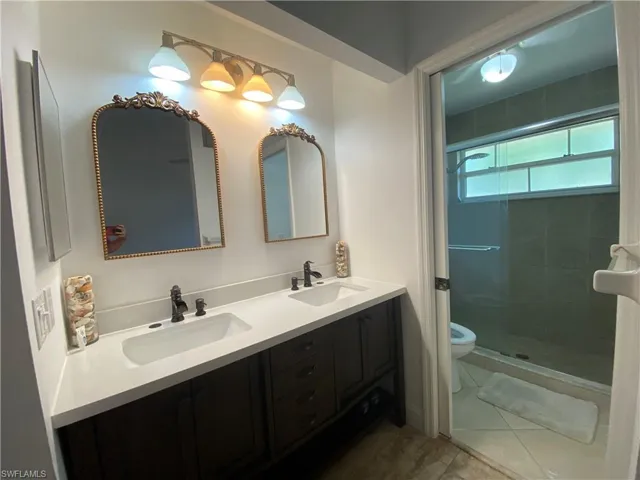 Full bathroom with double vanity and a stall shower