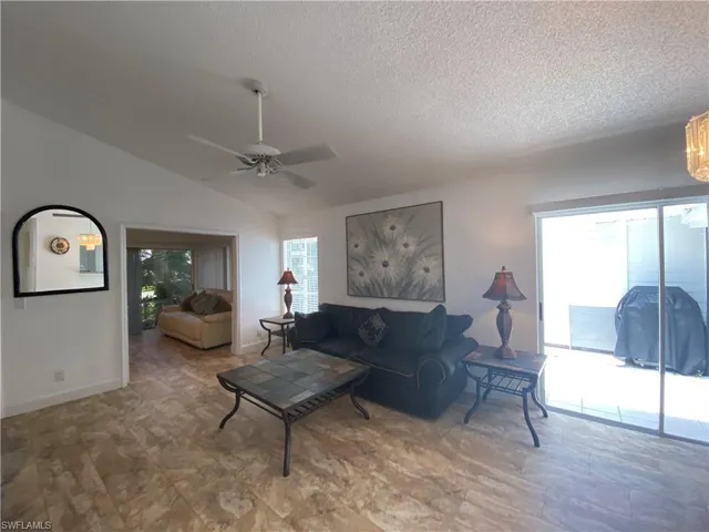 Living room featuring vaulted ceiling, a ceiling fan, and a textured ceiling