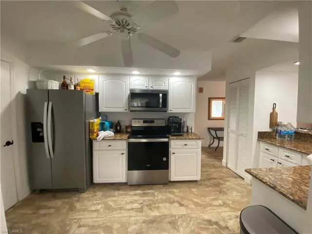 Kitchen featuring stainless steel appliances, dark stone countertops, white cabinets, recessed lighting, and ceiling fan