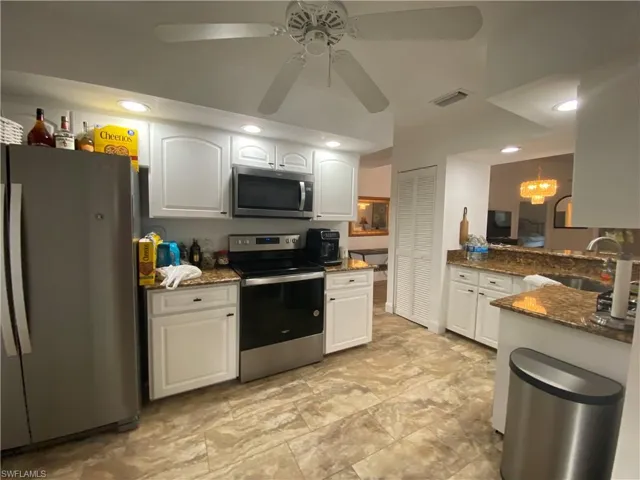 Kitchen featuring appliances with stainless steel finishes, dark stone countertops, white cabinetry, recessed lighting, and ceiling fan