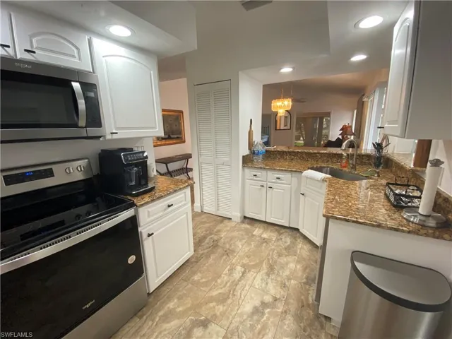 Kitchen with stainless steel appliances, dark stone counters, recessed lighting, and white cabinetry