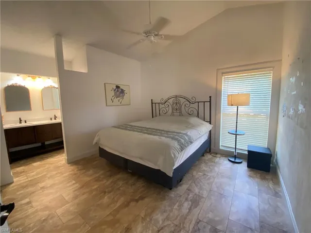 Bedroom with vaulted ceiling, ensuite bath, and a ceiling fan