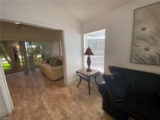 Living area with a textured ceiling, vaulted ceiling, plenty of natural light, and ceiling fan