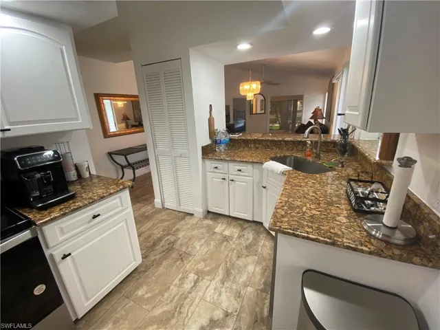 Kitchen featuring white cabinets, stainless steel range with electric stovetop, dark stone countertops, and ceiling fan