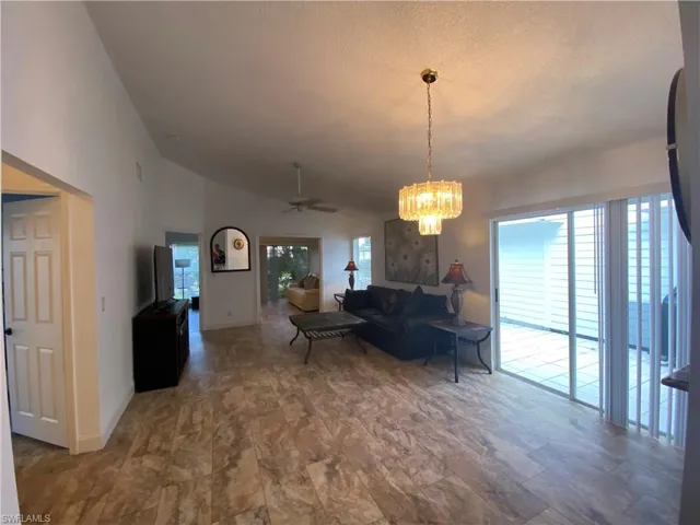 Living room featuring lofted ceiling, ceiling fan, a textured ceiling, and a chandelier