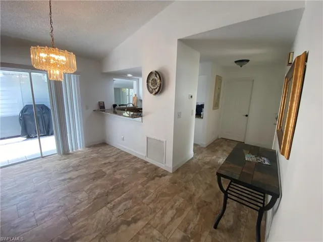 Dining space featuring a textured ceiling, vaulted ceiling, and a chandelier