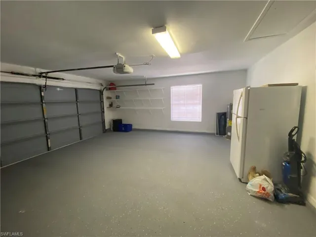 Garage featuring freestanding refrigerator and a garage door opener