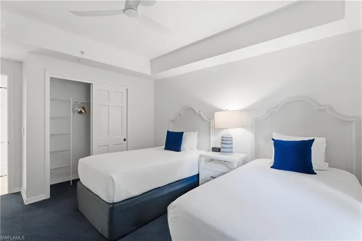Bedroom with a closet, dark colored carpet, and a ceiling fan