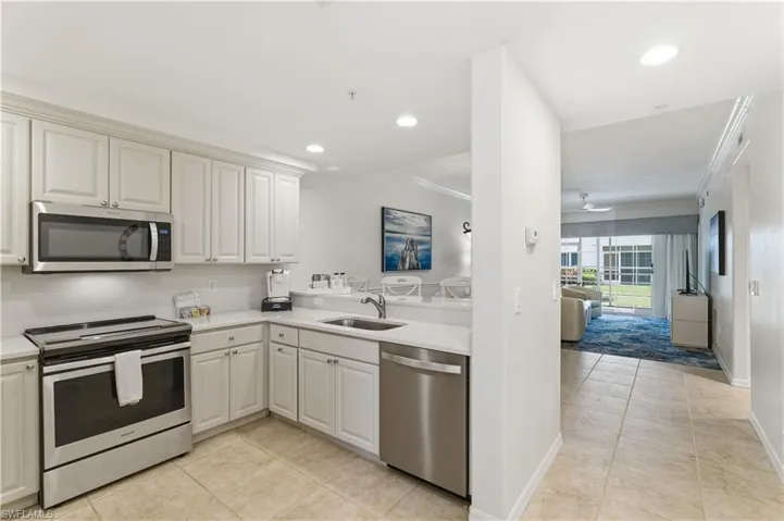 Kitchen featuring appliances with stainless steel finishes, light tile patterned floors, ornamental molding, open floor plan, and a peninsula