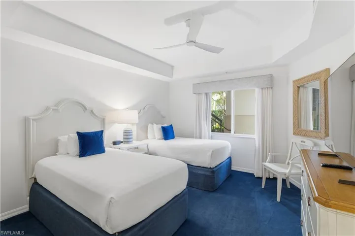 Bedroom with a raised ceiling, a ceiling fan, and dark carpet