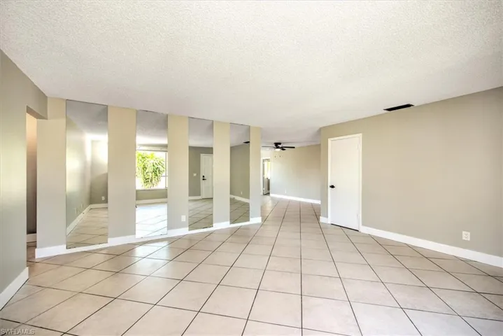 Unfurnished room with ceiling fan, light tile patterned floors, and a textured ceiling