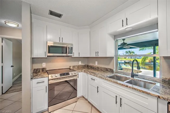 Kitchen featuring white cabinets, stainless steel appliances, a water view, and sink