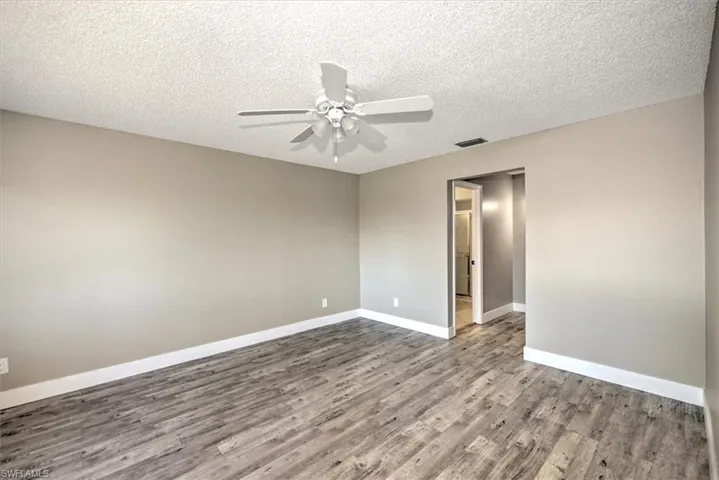 Empty room featuring ceiling fan, a textured ceiling, and hardwood / wood-style flooring