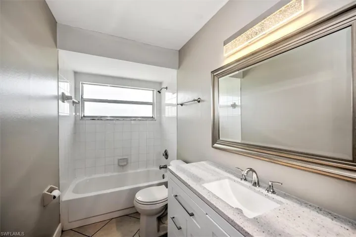 Full bathroom featuring tile patterned floors, vanity, tiled shower / bath combo, and toilet