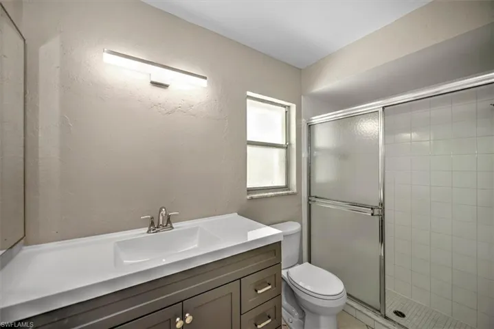 Bathroom with vanity, a shower with shower door, and toilet