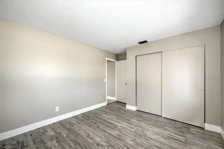 Unfurnished bedroom with a textured ceiling, light wood-type flooring, and a closet