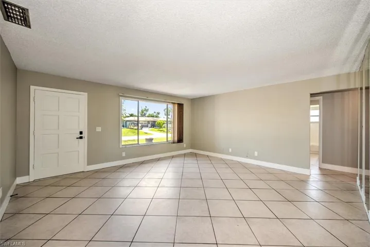 Empty room featuring light tile patterned flooring and a textured ceiling