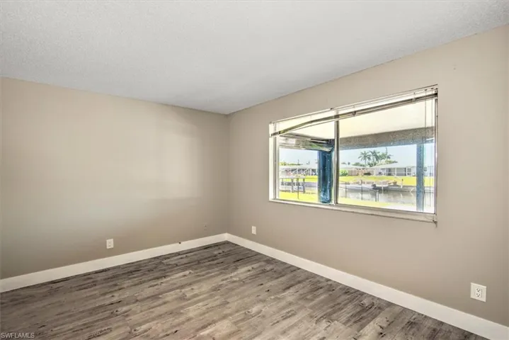 Spare room with a water view, wood-type flooring, and a textured ceiling