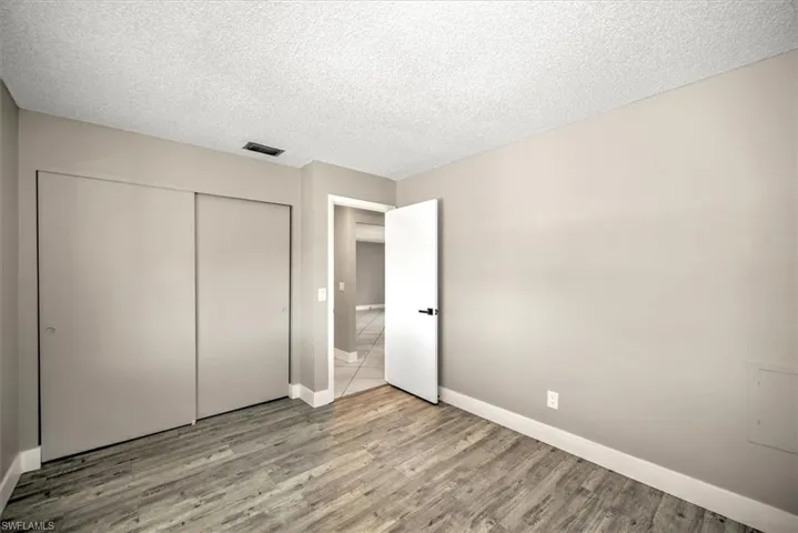 Unfurnished bedroom featuring light wood-type flooring, a textured ceiling, and a closet