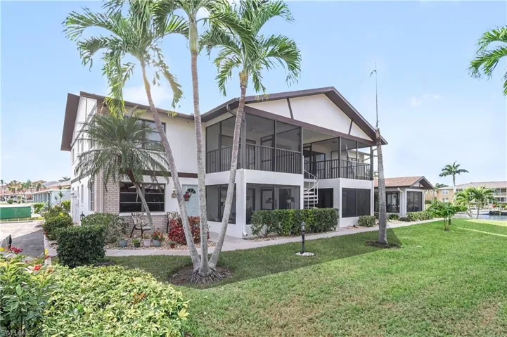 Back of house featuring a lawn, brick siding, a balcony, a sunroom, and stucco siding