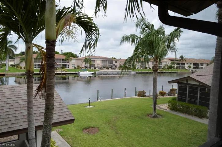 View of green lawn with a water view, a residential view, and a dock