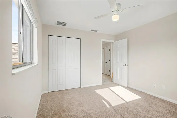 Unfurnished bedroom featuring light colored carpet, a closet, and ceiling fan